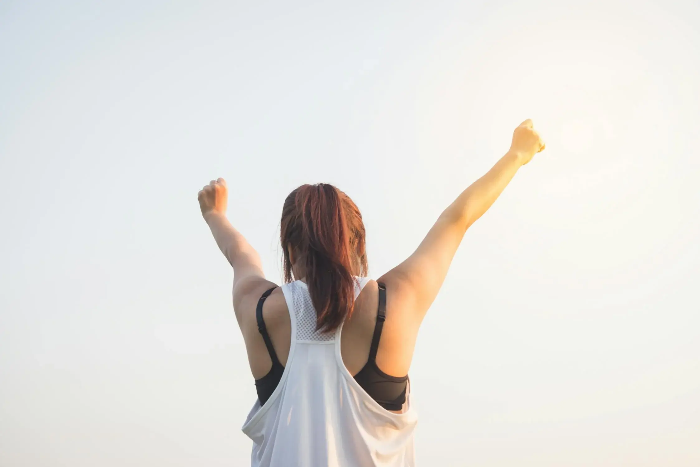 woman in white top throwing her hands up