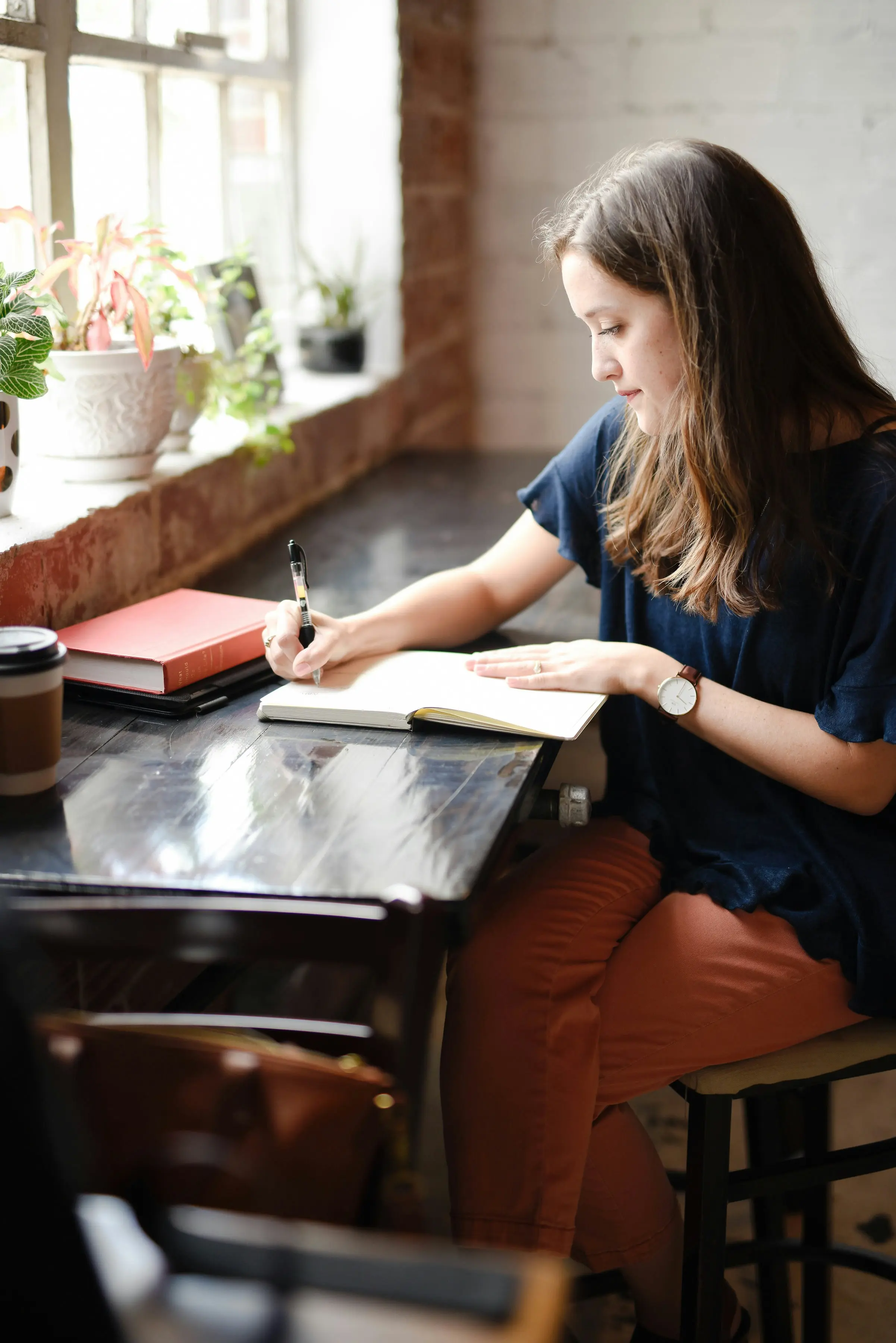 woman in blue shirt journaling on table